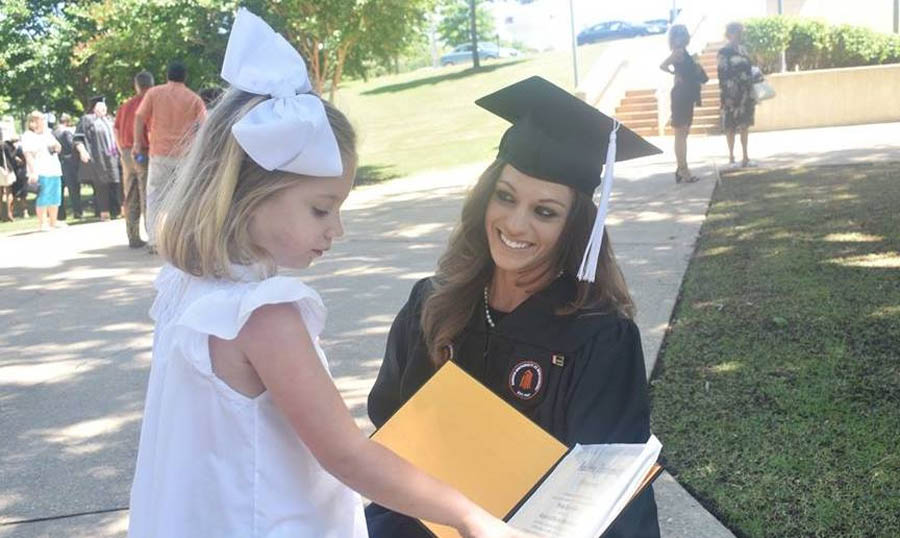 Shelby shows off her diploma to her 5-year-old daughter, Laura Leigh.