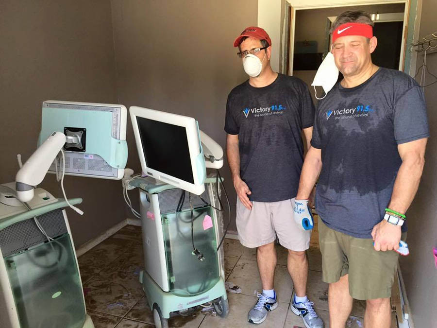 Community volunteers stand beside two of the three destroyed ultrasound units at Care Pregnancy Clinic