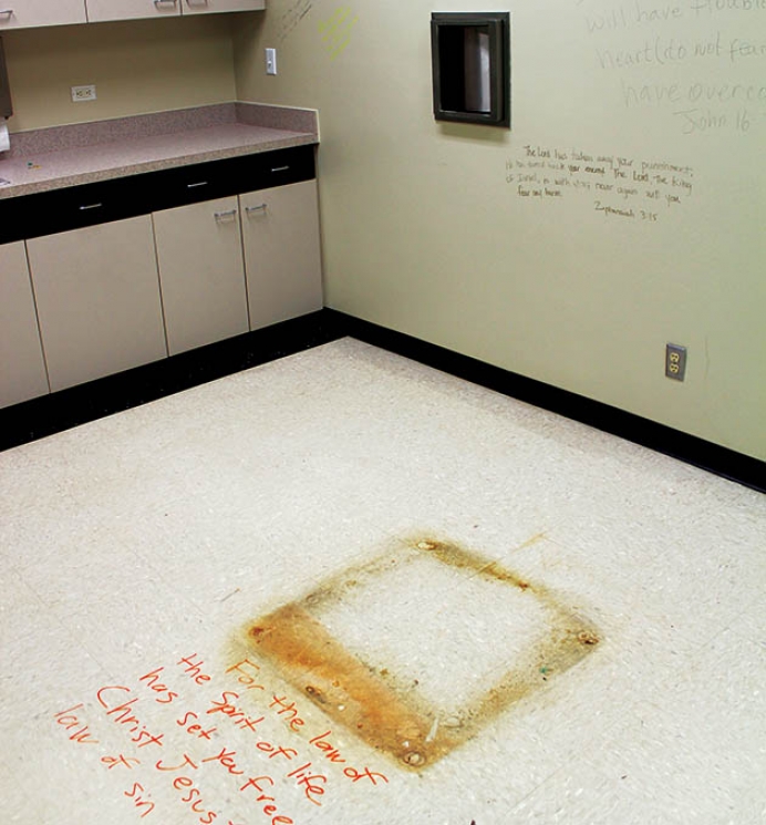 Former abortion procedure room where pro-life advocates have inscribed the walls and floor with Scripture. The floor stain marks the location of the surgical table and the steel carousel in the wall transferred the aborted fetus to the biohazard waste.